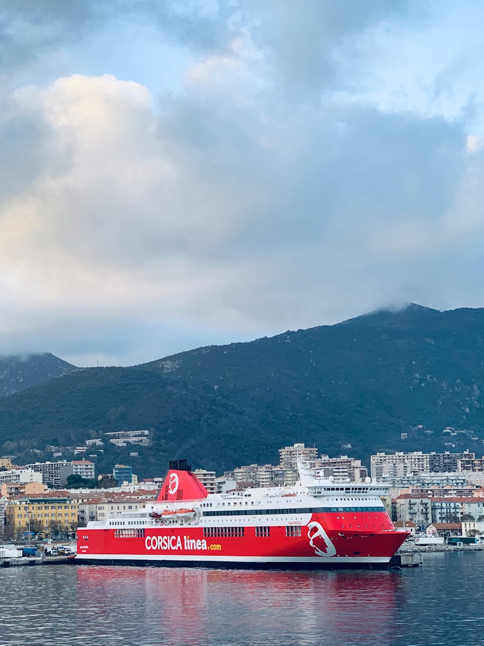 Ferry amarré dans le port d'Ajaccio avec la ville et les montagnes en fond