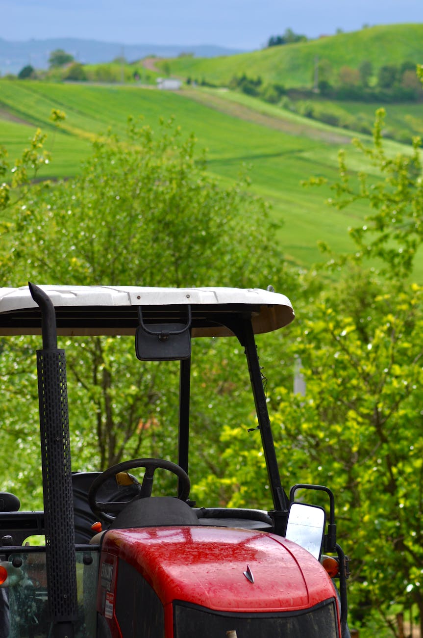 Tracteur rouge dans un paysage agricole verdoyant