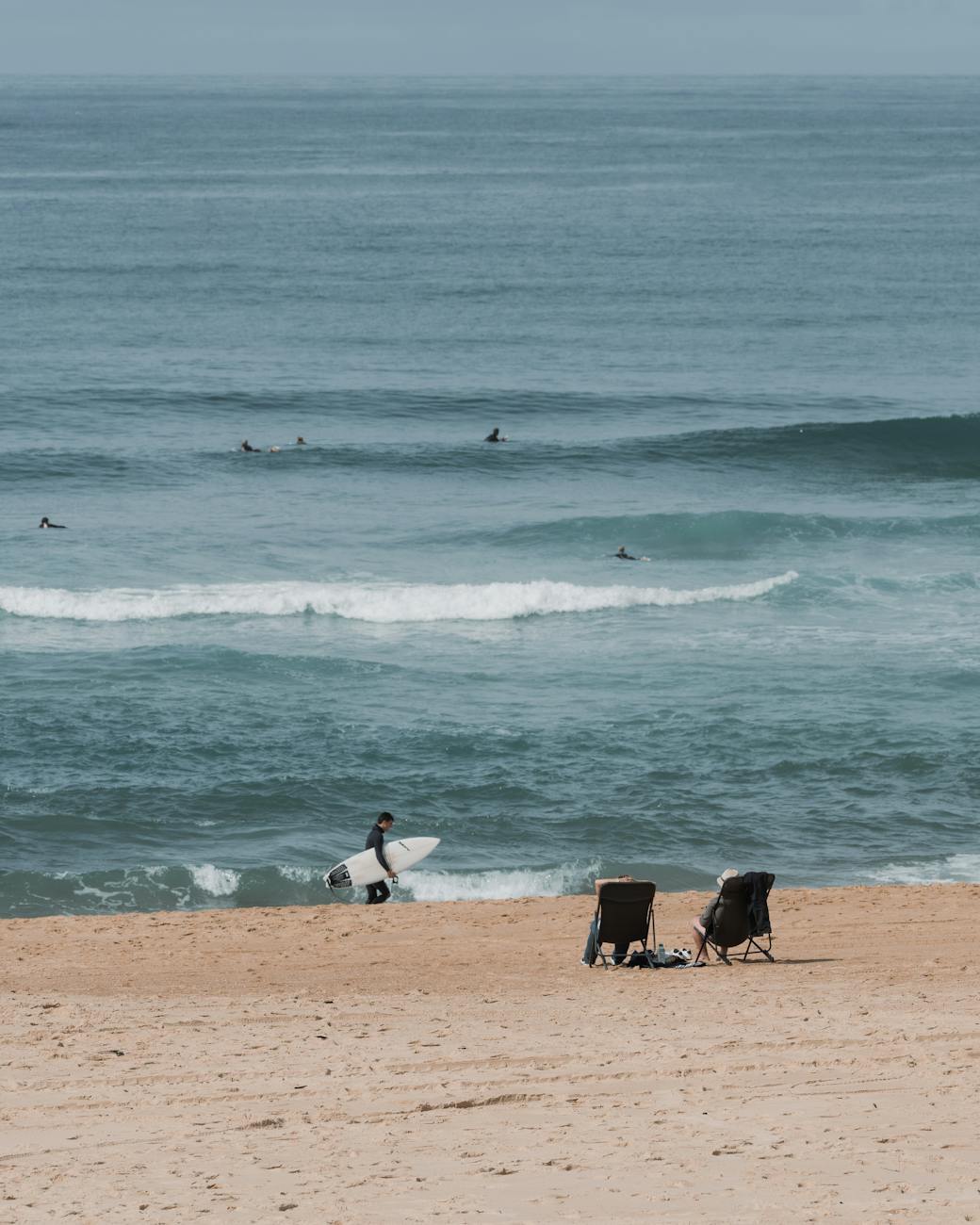 Surfeur marchant sur la plage de sable, côte du Sud-Ouest