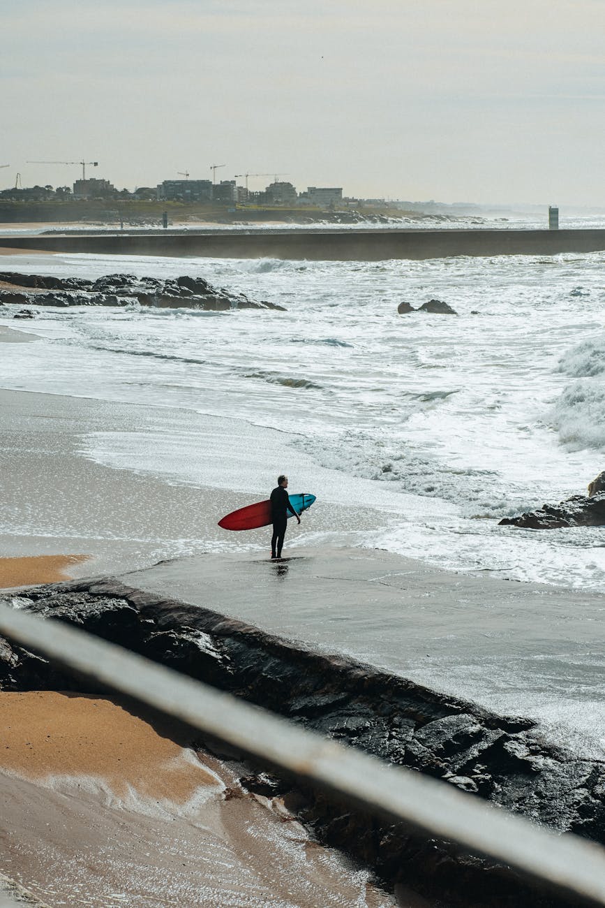 Surfeur solitaire et planches sur plage rocheuse