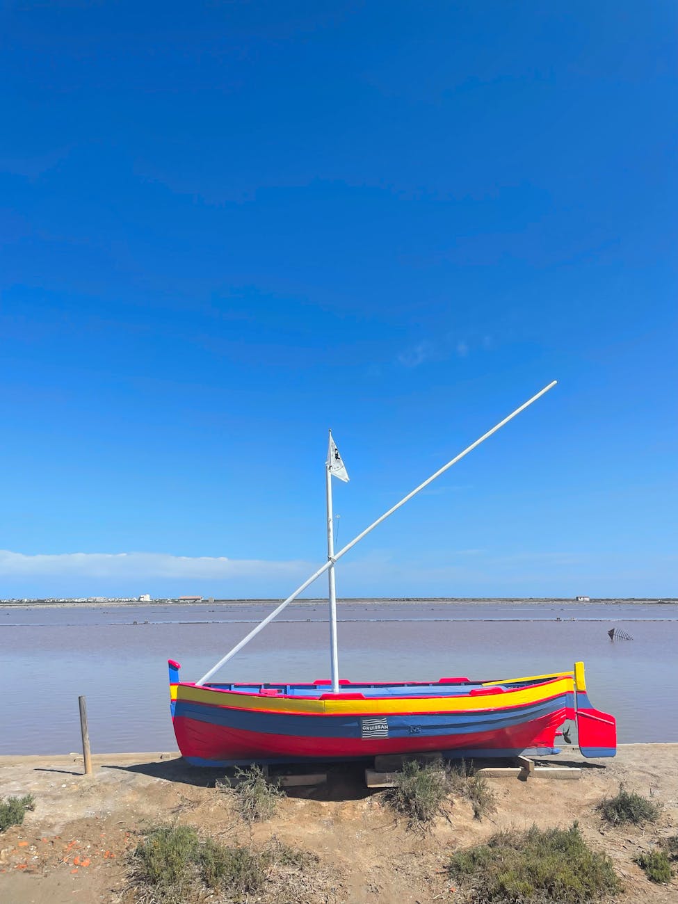 Barque colorée sur la plage de Gruissan sous un ciel bleu méditerranéen