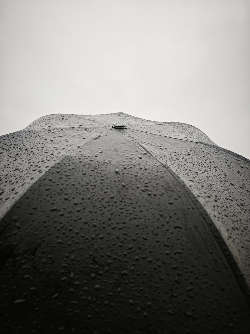 Parapluie noir avec gouttes de pluie en gros plan sur un ciel gris