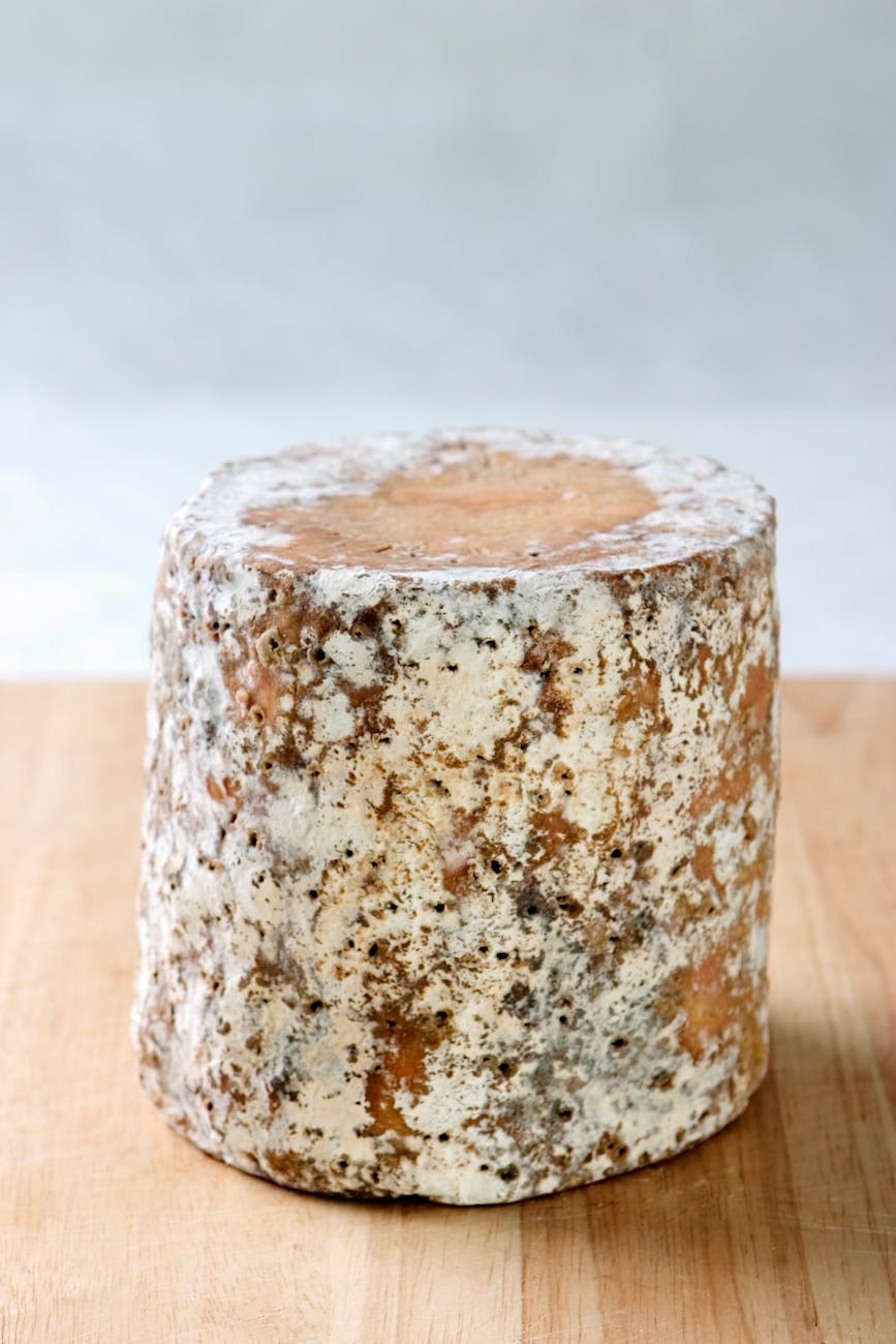 Gros plan d'une meule de fromage rustique sur une table en bois, texture affinée