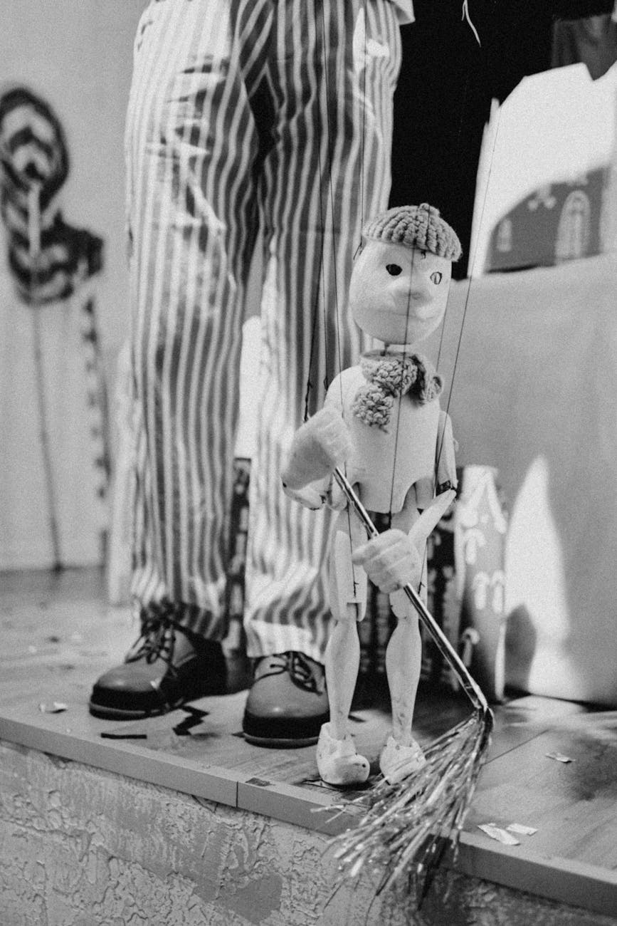 Image en noir et blanc captivante d'une marionnette et d'un performeur en pantalon rayé