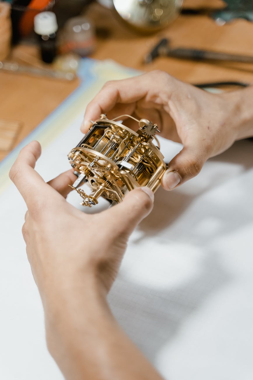 Mains tenant un mécanisme d'horlogerie en atelier