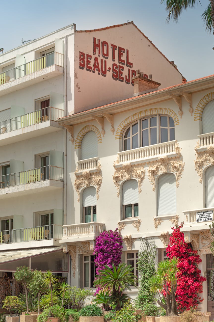 Façade d'hôtel ornée de fleurs et palmiers sous un ciel ensoleillé