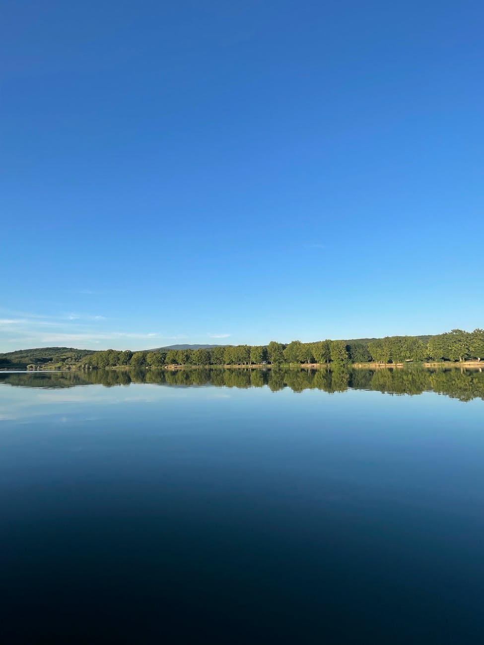 Lac tranquille reflet du ciel et rive verdoyante