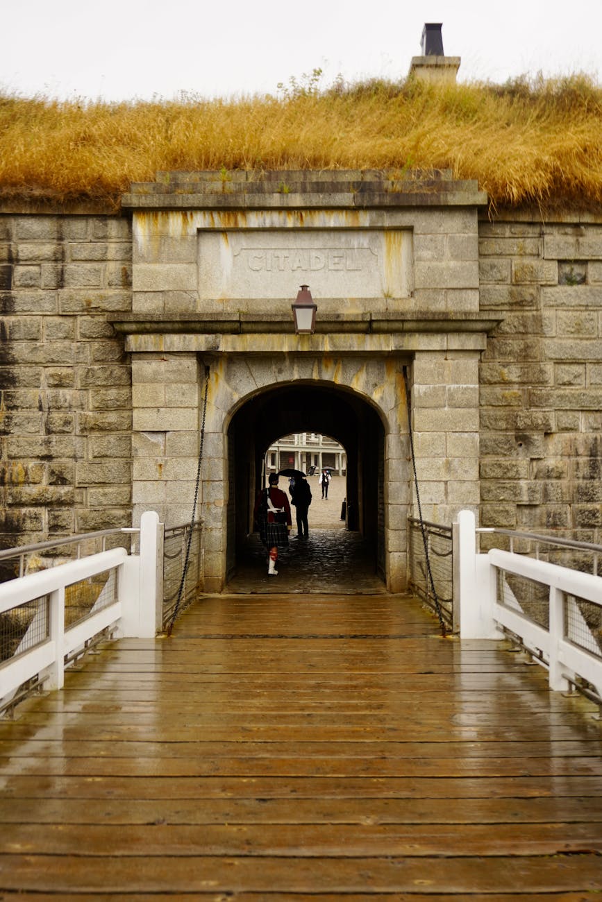 Entrée historique en pierre d'une citadelle avec des visiteurs un jour de pluie