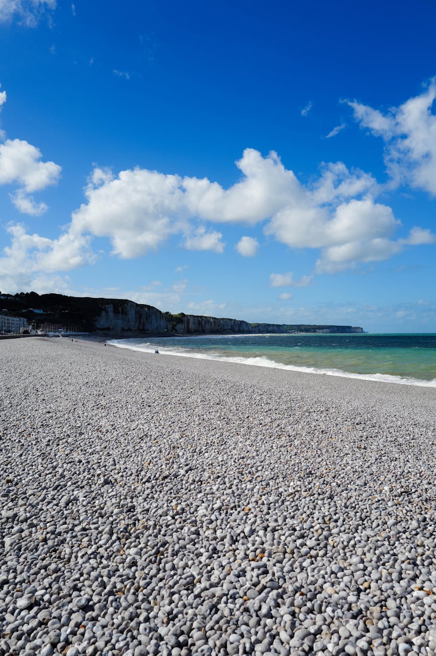 Plage de galets sous un ciel nuageux en Normandie