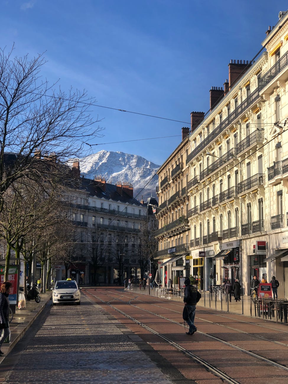 Rue de Grenoble avec architecture historique et massif alpin en arrière-plan