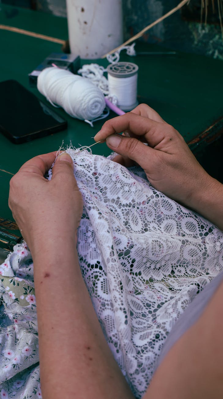 Mains travaillant la dentelle aux fuseaux sur tissu