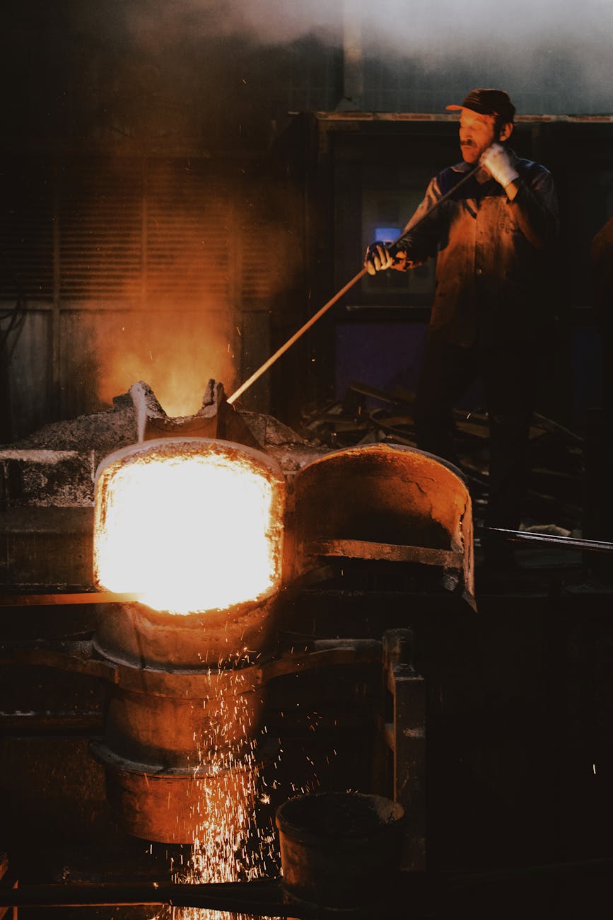 Ouvrier de fonderie versant du métal en fusion avec étincelles