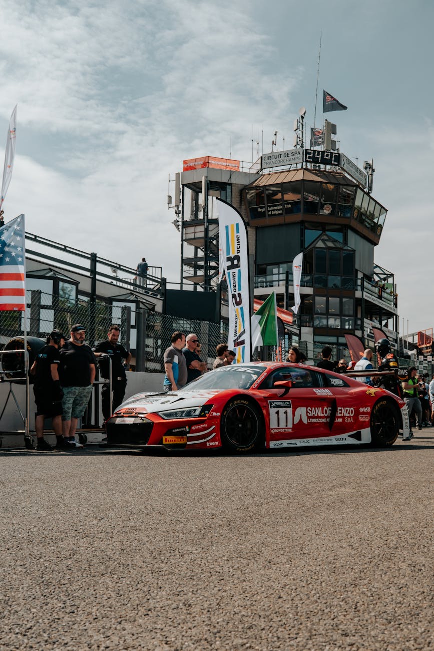 Voiture de course rouge à un stand pendant un événement motorsport