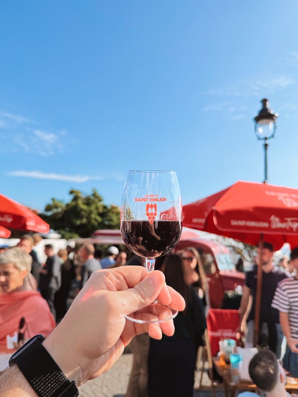 Main tenant un verre de vin lors d'un festival à Saint-Émilion