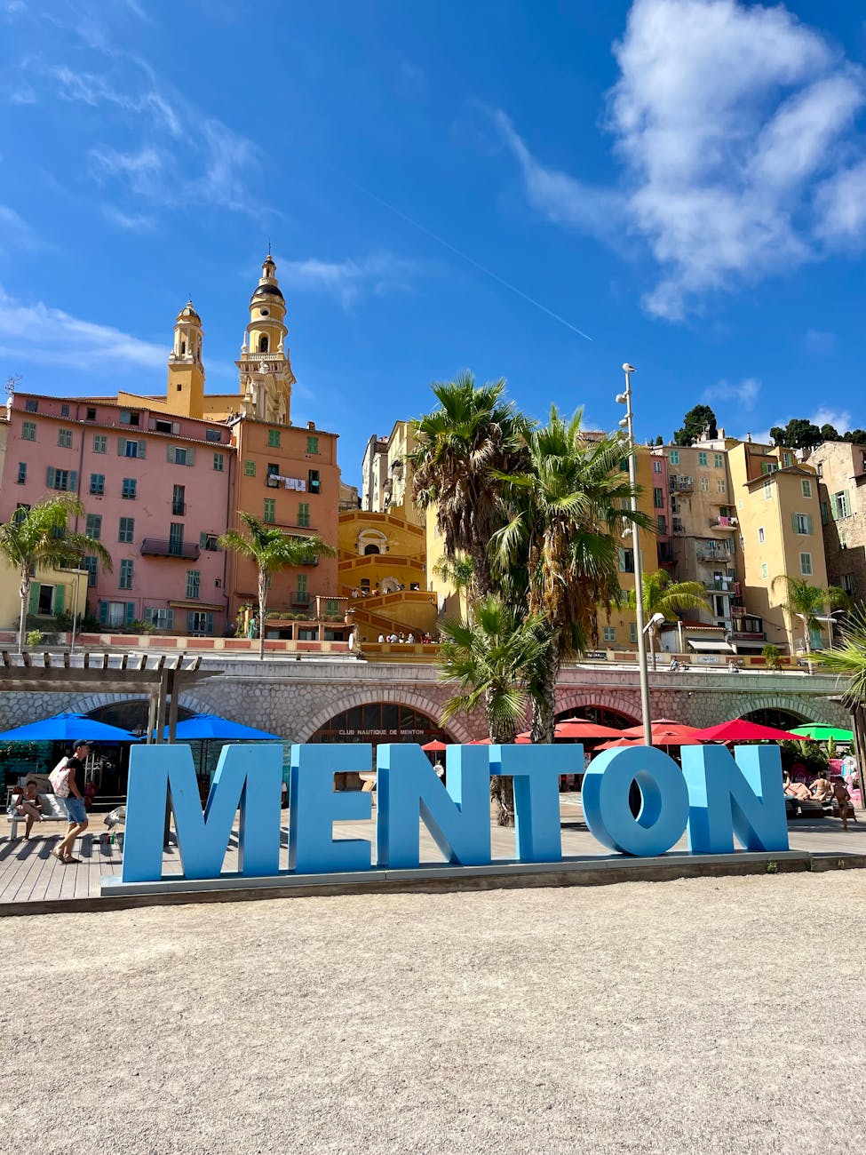 Façades pastel et palmiers de Menton sous un ciel ensoleillé