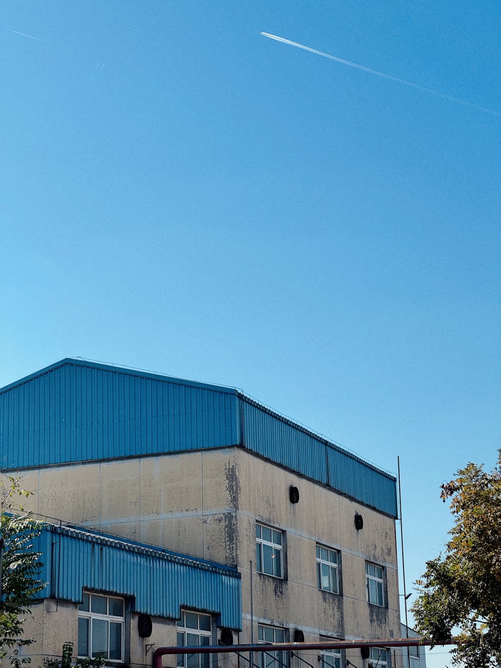 Bâtiment industriel sous ciel bleu avec passage d'avion
