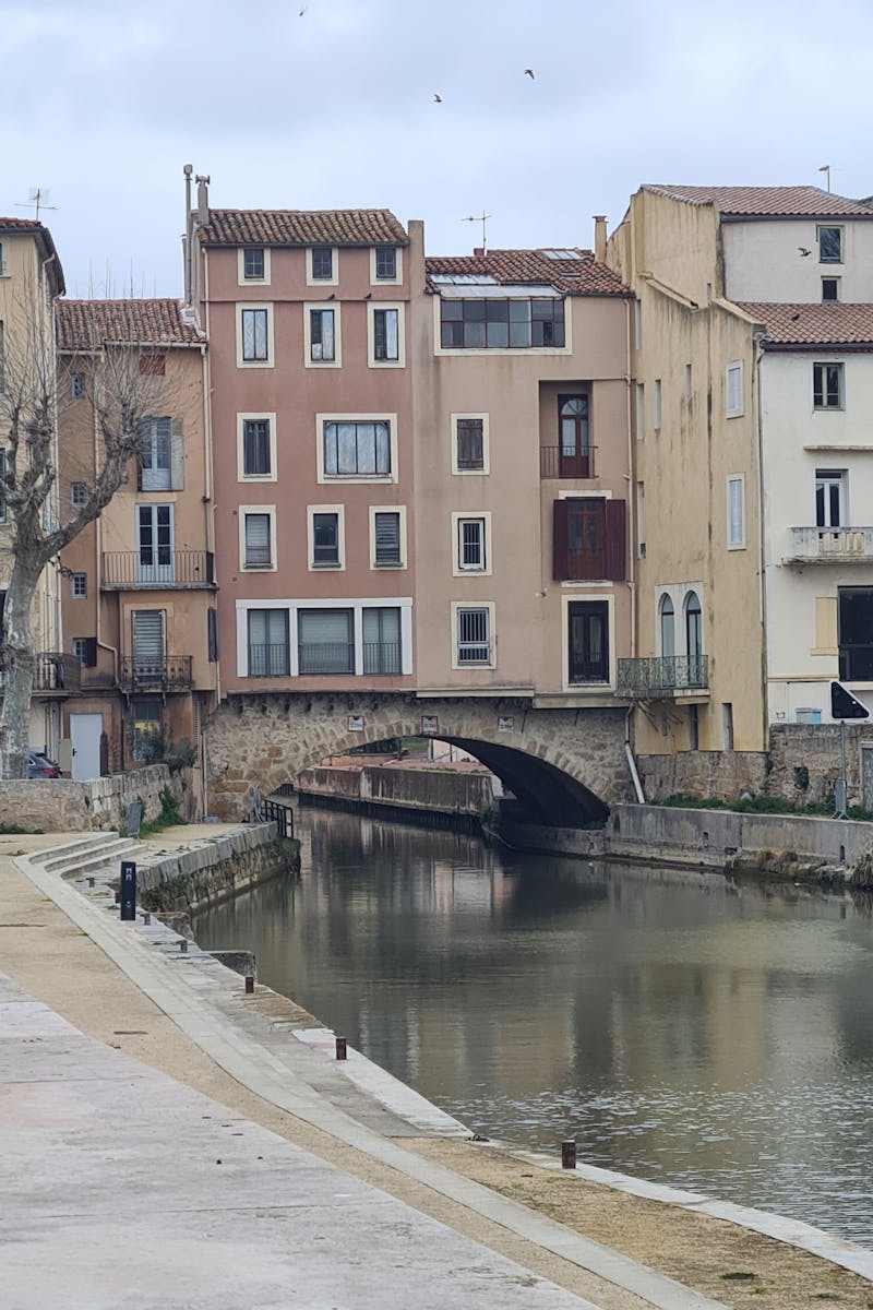 Pont historique sur le canal de la Robine à Narbonne avec immeubles colorés