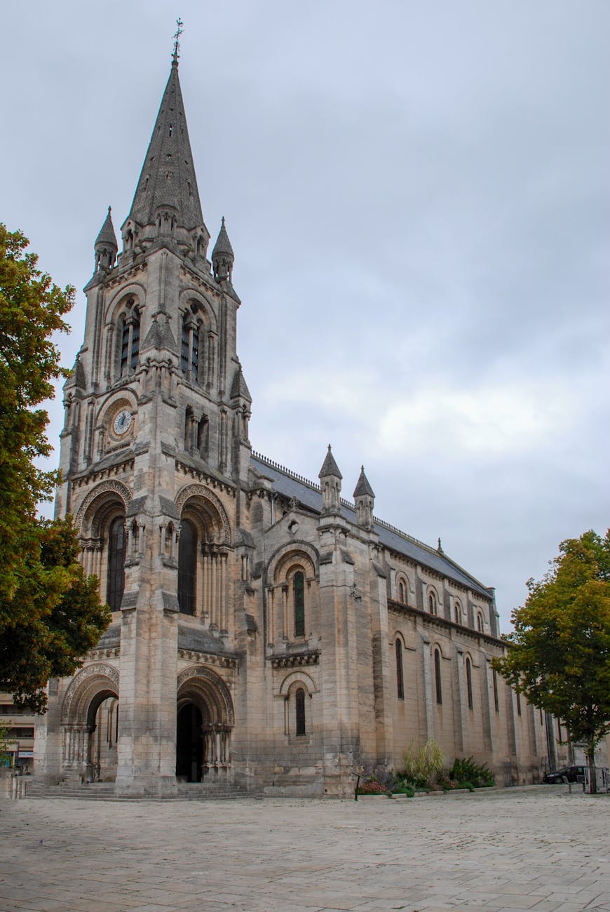 Façade et flèche d'une église gothique sous un ciel nuageux