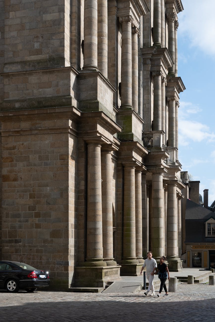 Couple sur une rue pavée devant un grand bâtiment de Rennes