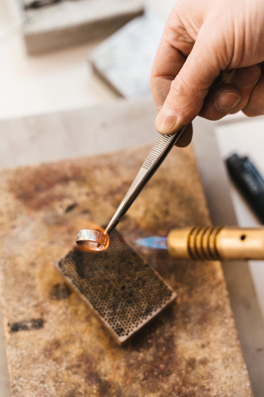 Bijoutier utilisant un chalumeau et une pince pour fabriquer une bague en métal