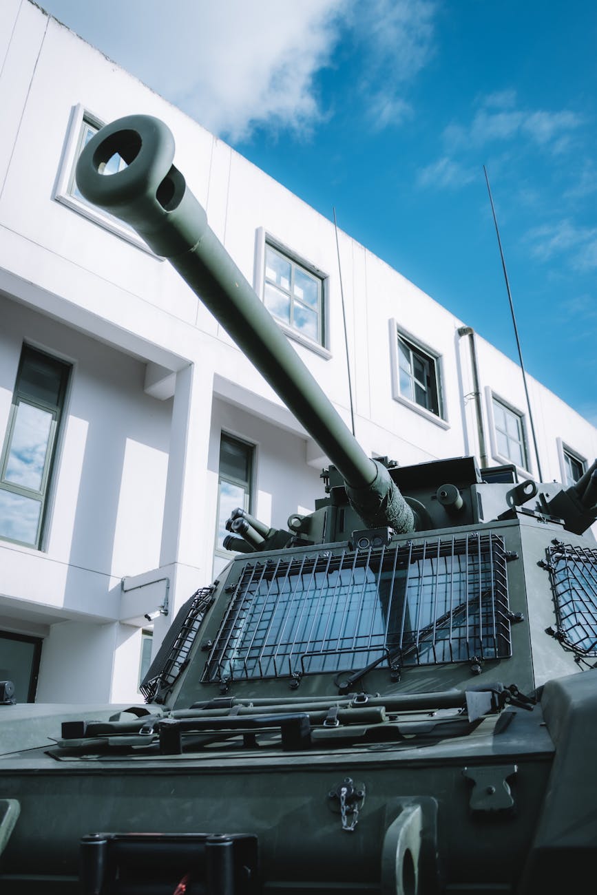 Char militaire devant un bâtiment moderne sous ciel bleu