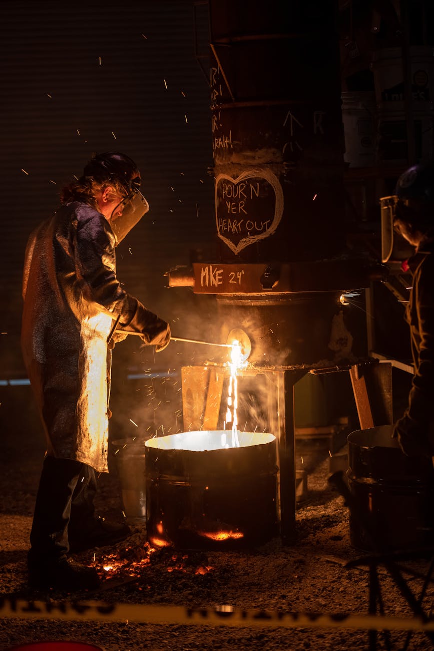 Ouvrier coulant du métal en fusion en fonderie industrielle