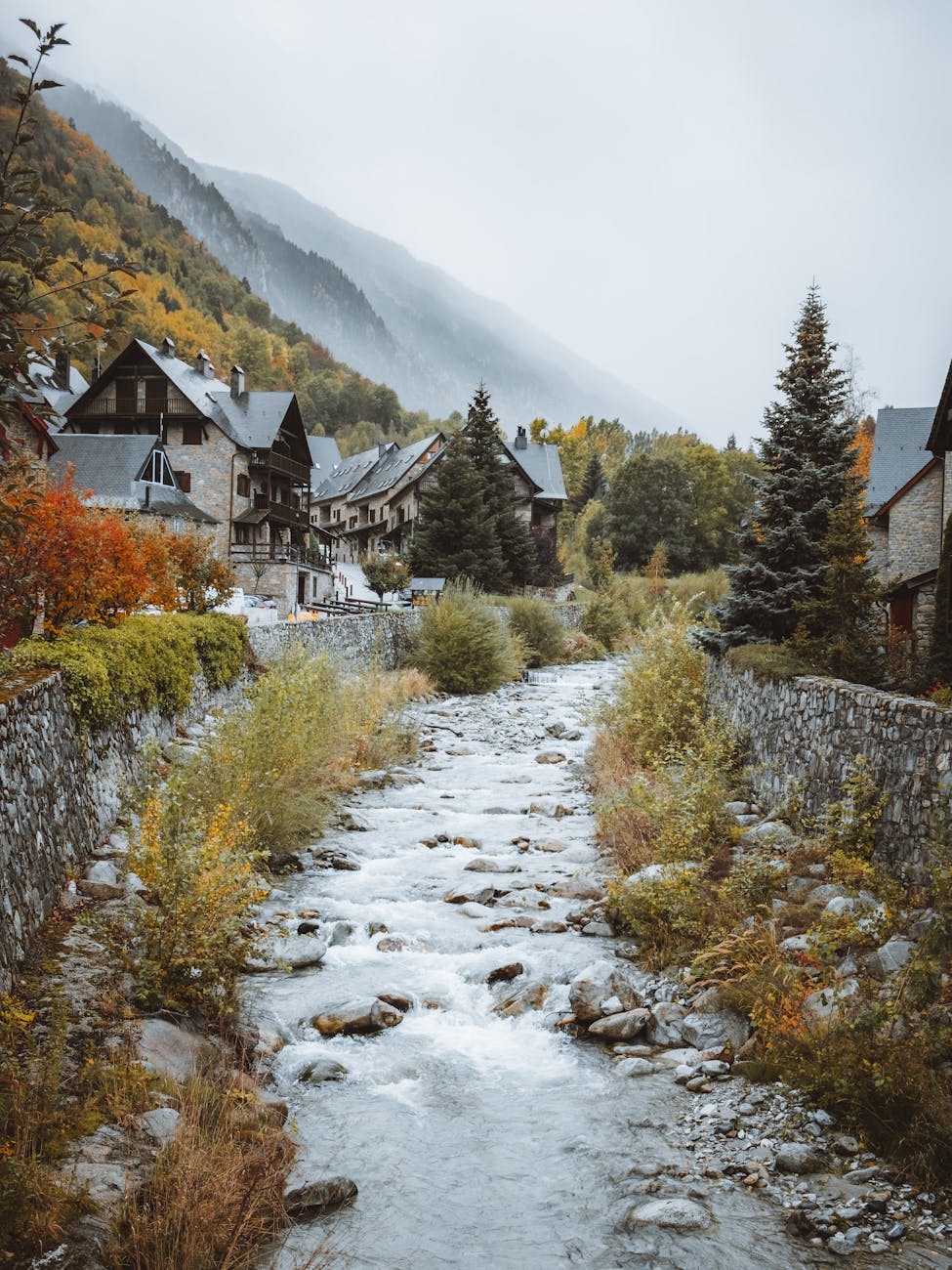 Maisons de pierre alignées le long d'un ruisseau pyrénéen aux couleurs d'automne