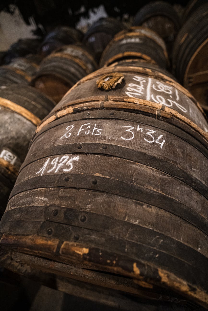 Fûts de chêne empilés dans un chai de cognac avec lumière chaude