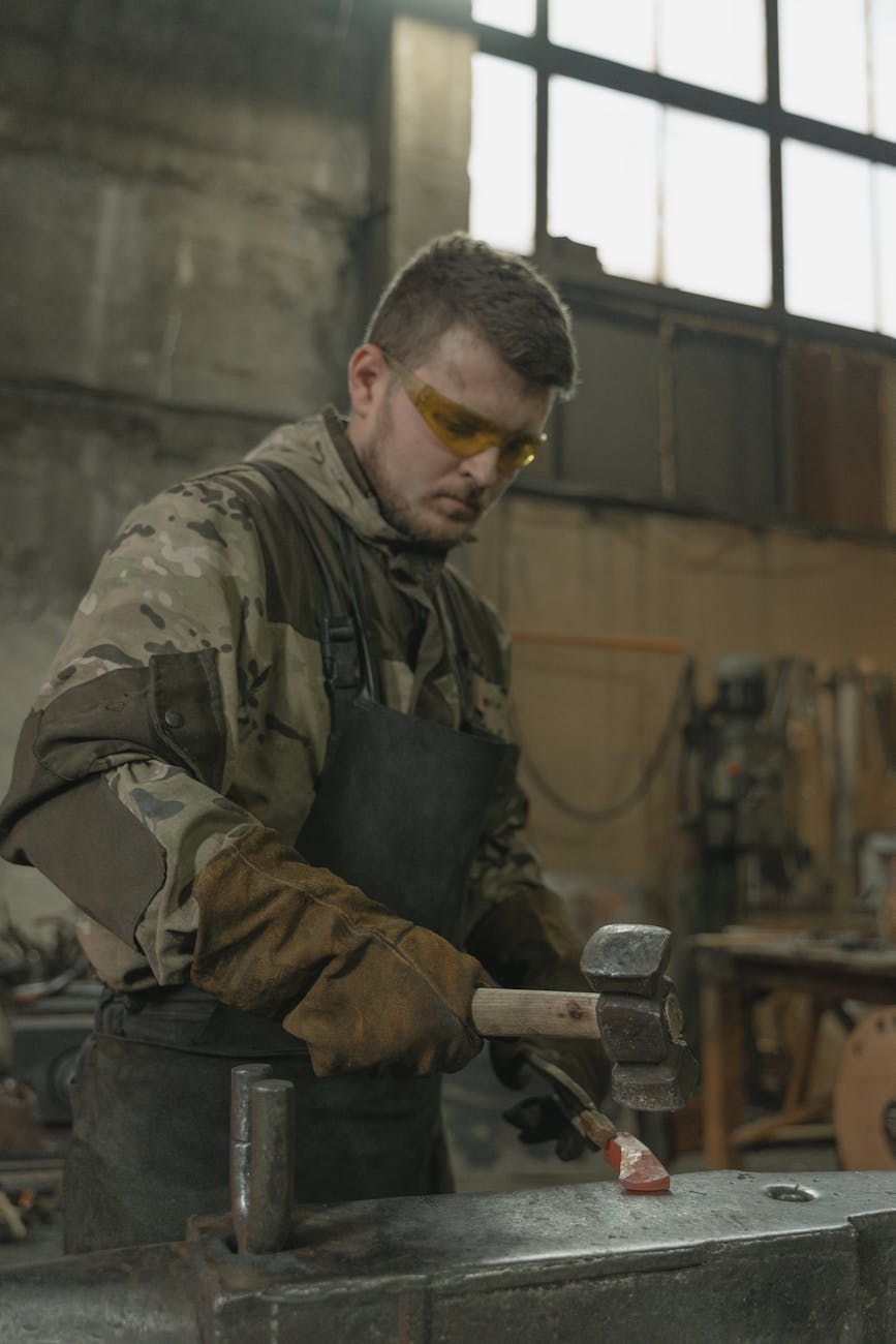 Forgeron concentré martelant du métal chaud dans un atelier industriel