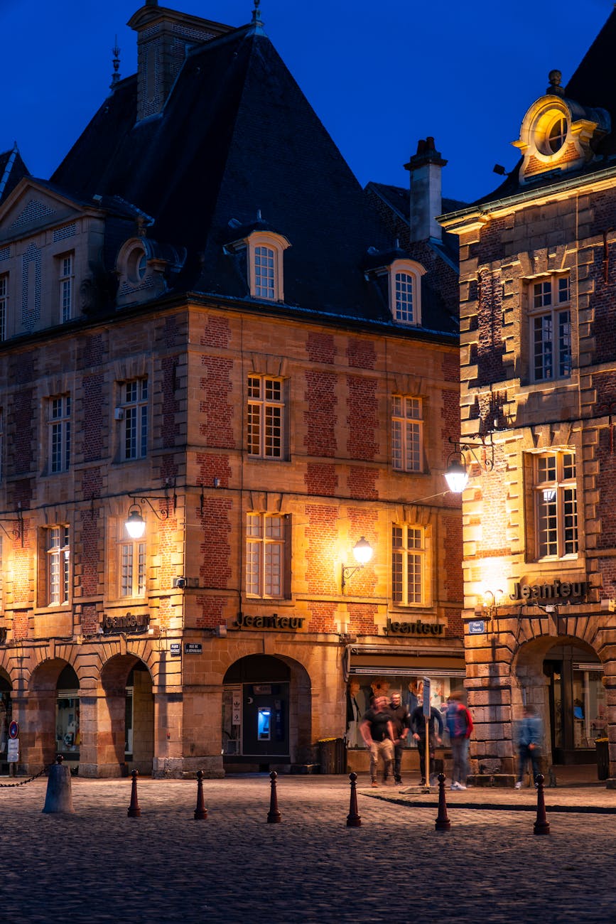 Bâtiment historique illuminé la nuit avec passants sur pavés