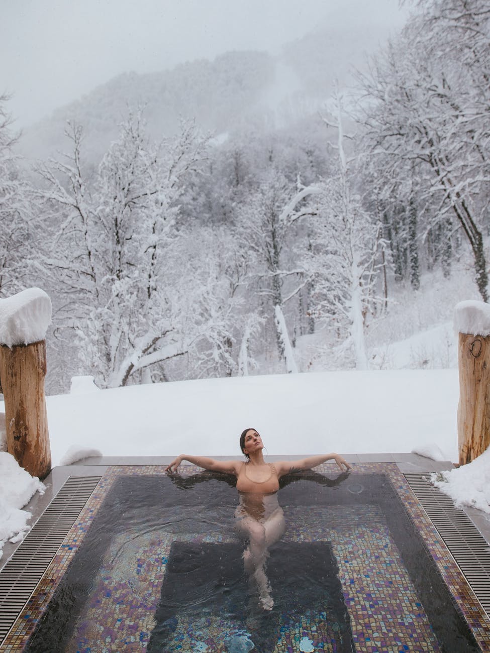 Femme dans un bassin thermal entouré de neige