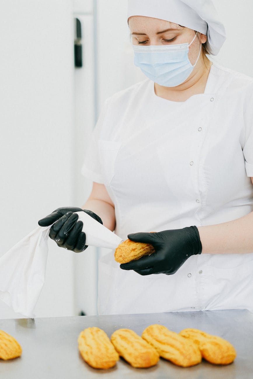 Pâtissier en tenue garnissant des éclairs en cuisine professionnelle